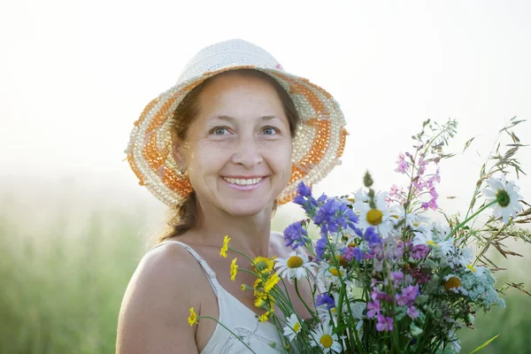 Zralá žena s květy kytička — Stock fotografie
