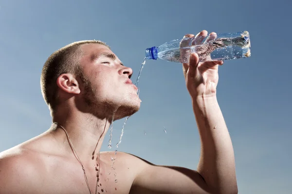 The young man pours water from a bottle — Stock Photo, Image