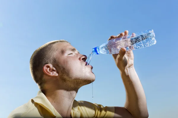 Mladý muž nalévá vodu z láhve — Stock fotografie