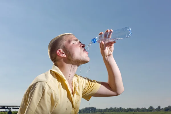 Young man pours water from a bottle — Stock Photo, Image