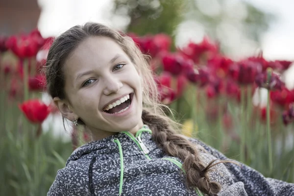 Het mooie meisje lacht tegen tulpen — Stockfoto