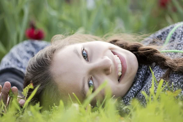Vacker flicka skrattar mot tulpaner — Stockfoto