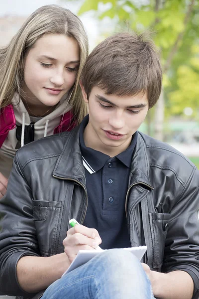 Het meisje en de jonge man schrijven in een notitieblok — Stockfoto
