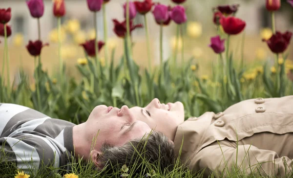 Мужчина и женщины лежат на кровати с тюльпанами — стоковое фото