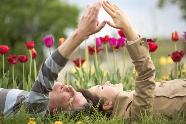 The man and the women are lying against a bed with tulips — Stock Photo, Image