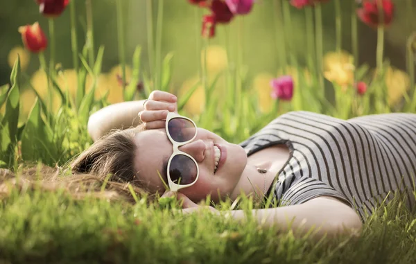 Flickan ligger på en säng med tulpaner — Stockfoto