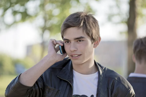Młody człowiek rozmawiający przez telefon w parku — Zdjęcie stockowe