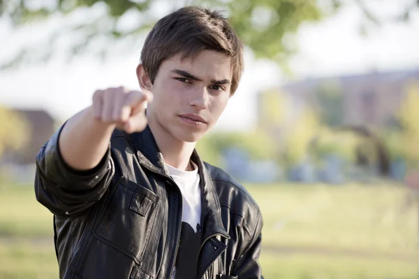 Portrait of young man pointing with finger against a nature background — Stock Photo, Image