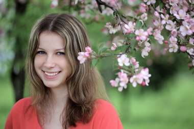 tam çiçeklenme zamanında bir elma bahçesi içinde genç bir kadın.