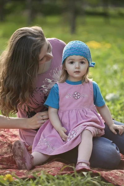Молодая заботливая мать утешает маленькую девочку на лугу — стоковое фото