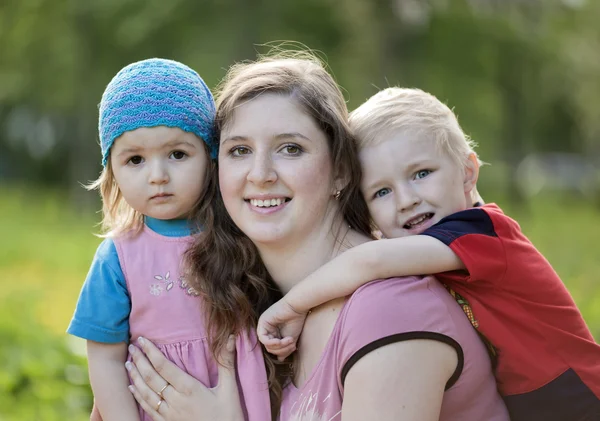 Portrait of beautiful happy smiling mother with children outdoor, on nature