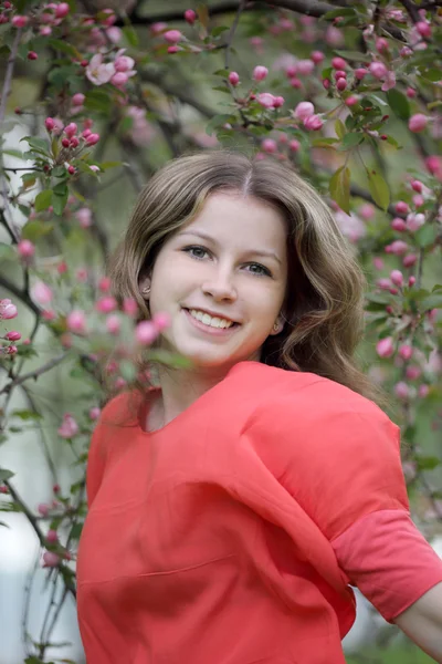 Eine junge Frau in einem Apfelgarten zur Zeit der vollen Blüte. — Stockfoto