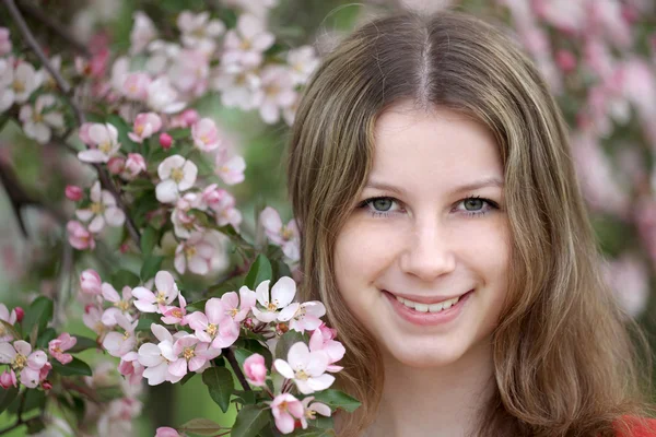 Een jonge vrouw in een appelboomgaard op het moment van volledige bloei. — Stockfoto