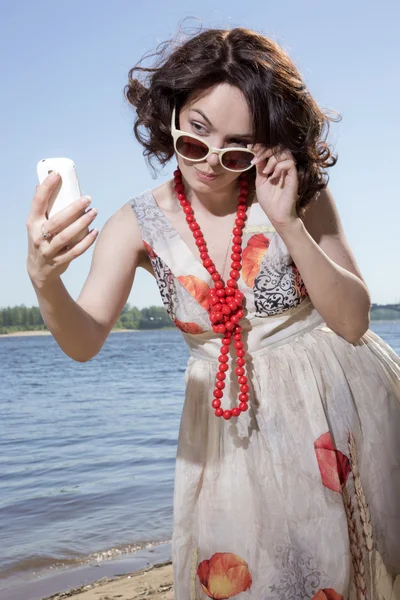 A menina em óculos de sol olha para o telefone — Fotografia de Stock