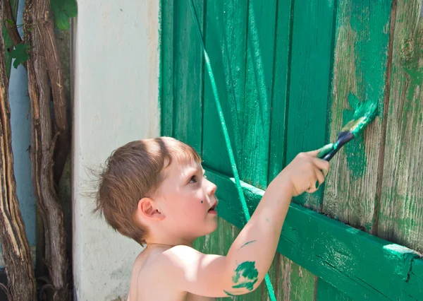 Мальчик красит забор — стоковое фото