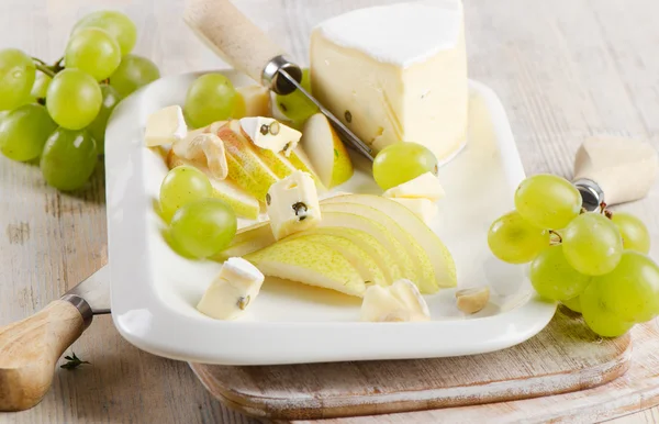 Сир і виноград на дерев'яній тарілці — стокове фото