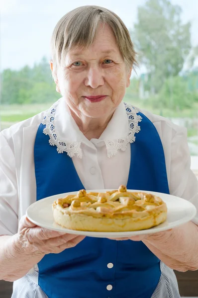 Felice donna anziana sorridente mostrando la sua torta di mele — Foto Stock