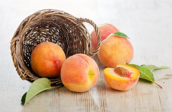 Fresh peaches in the basket on a wooden table — Stock Photo, Image