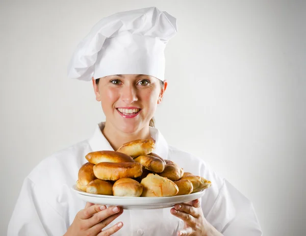 Mujer joven chef sosteniendo un plato con pasteles —  Fotos de Stock