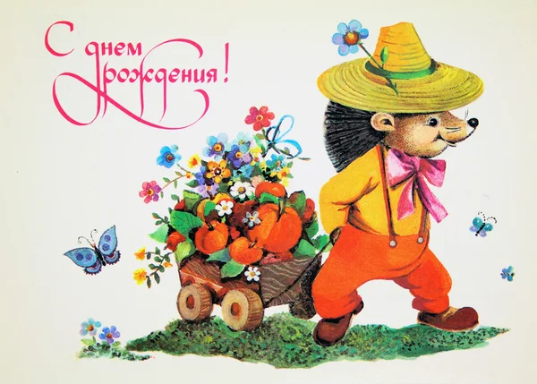 Ежик в шляпе и комбинезоне носит тележку с фруктами — стоковое фото