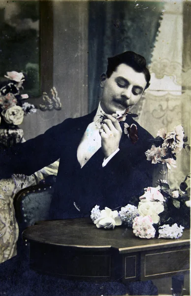 Człowiek uważa kwiaty siedzi przy stole — Zdjęcie stockowe
