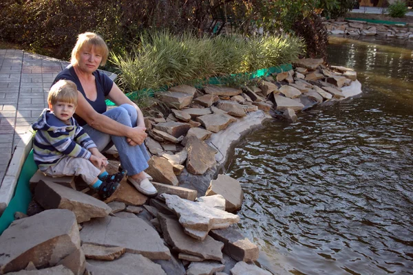 祖母と孫の池の上に座って — ストック写真