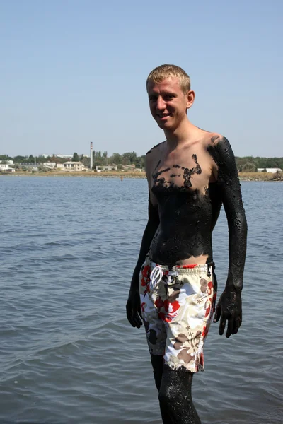 Junger Mann im salzigen See mit Schlamm bedeckt — Stockfoto
