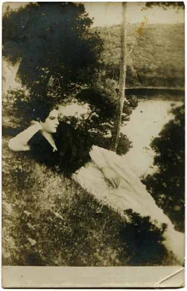 Sad woman lying on the bank of the river — Stock Photo, Image