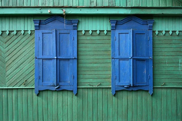 Zwei blaue Fenster an einer grünen Wand — Stockfoto