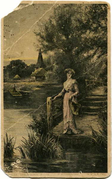 Женщина в длинном платье стоит на берегу пруда — стоковое фото