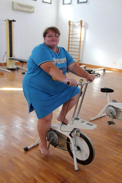 Mujer con sobrepeso haciendo ejercicio en bicicleta —  Fotos de Stock