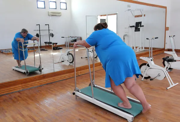 Overgewicht vrouw draait op trainer loopband — Stockfoto