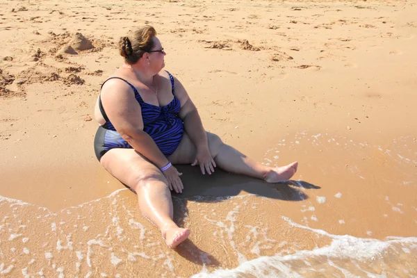 Übergewichtige Frau sitzt am Strand — Stockfoto
