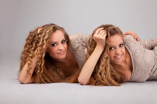 Due gemelle ragazze, isolate sullo sfondo grigio — Foto Stock