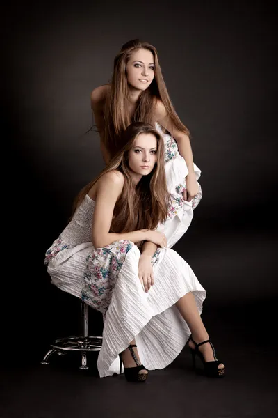 Två flickor tvillingar, isolerad på grå bakgrund — Stockfoto