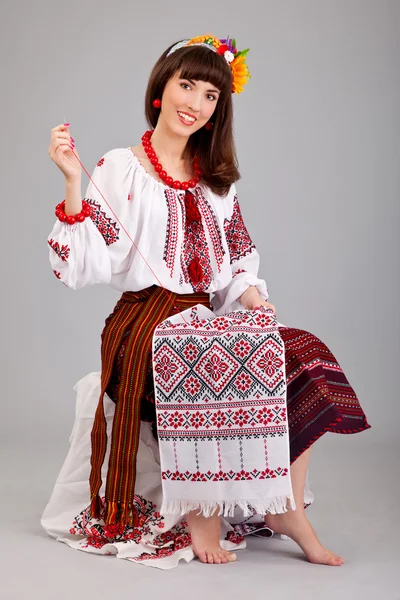 Donna attraente indossa abito nazionale ucraino sta cucendo — Foto Stock