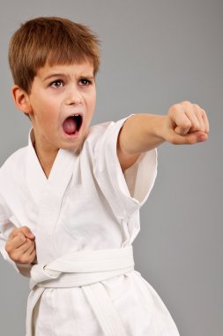 Beyaz kimonolu karateci çocuk dövüşüyor.