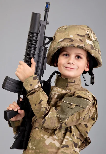 Mladý chlapec, oblečený jako voják s puškou — Stock fotografie
