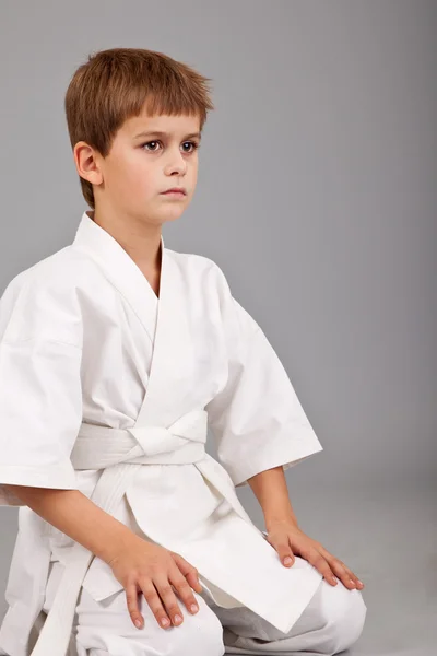 Karate-Junge im weißen Kimono sitzt — Stockfoto