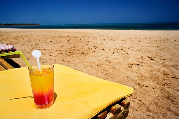 Glass of juice next to beach. — Stock Photo, Image