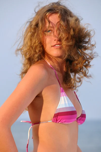 Красива молода жінка з літаючим волоссям біля моря на заході сонця — стокове фото