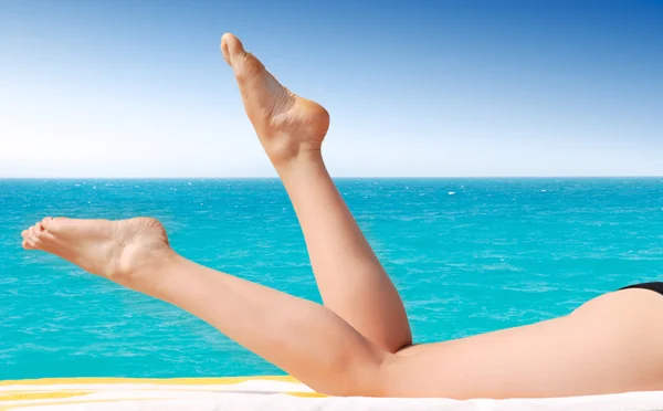 性感的女性双腿反对绿松石海 — 图库照片