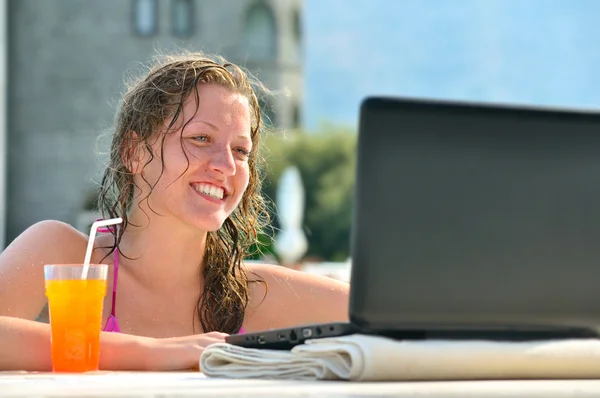 Woman is using laptop from swimming pool near the hotel Stock Picture