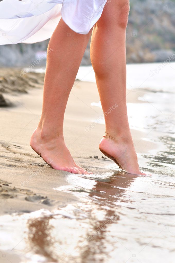 Slim female legs steps to the sea
