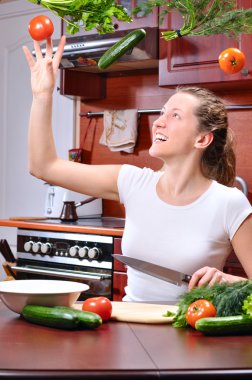 mutlu bir kadın dışarı uçan sebze salatası pişirme