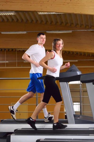 Attractive couple is running on the treadmill — Stock Photo, Image