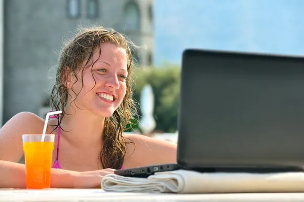 Mujer está utilizando el ordenador portátil de la piscina cerca del hotel — Foto de Stock