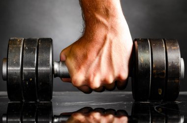 Male hand is holding metal barbell clipart