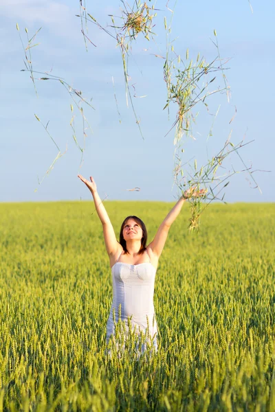 Chica en un campo de trigo lanza espigas — Foto de Stock