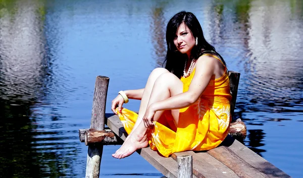 Linda morena senta-se em uma ponte — Fotografia de Stock